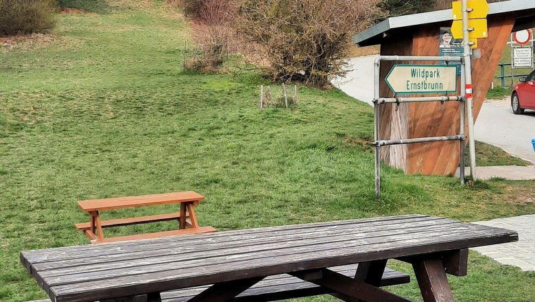 Motorhome parking space, © Bernhard Zechner Picnic table on a meadow with a forest in the background and a sign for Ernstbrunn Wildlife Park.