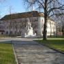 Minoritenkloster, © Gemeinde Asparn Ein historisches Gebäude mit rosa Fassade und einem Brunnen im Vordergrund.
