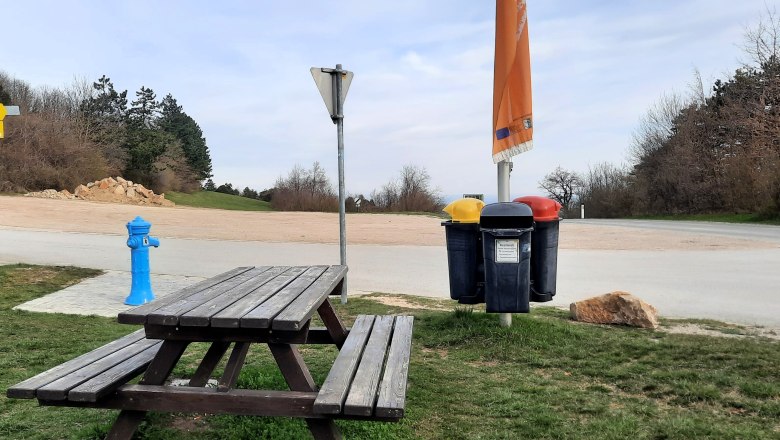 Motorhome parking space, © Bernhard Zechner Picnic table and garbage can in a parking lot with trees in the background.