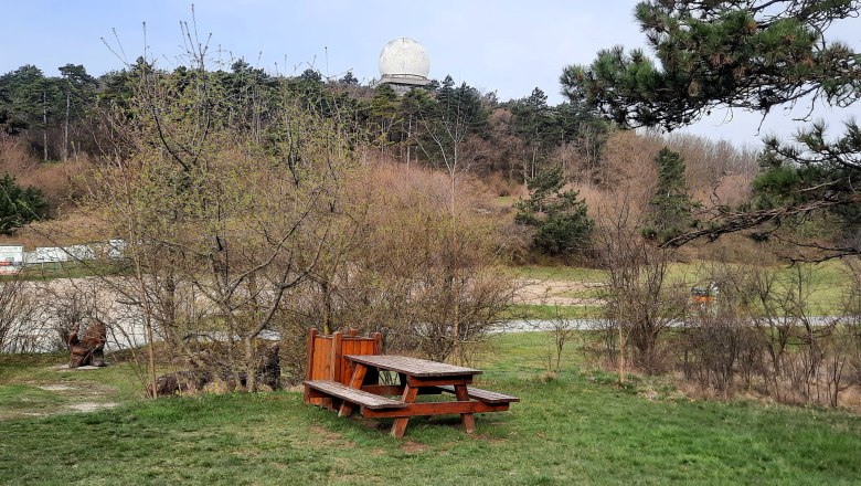 Motorhome parking space, © Bernhard Zechner Picnic table on a meadow with trees and a large white radome in the background.