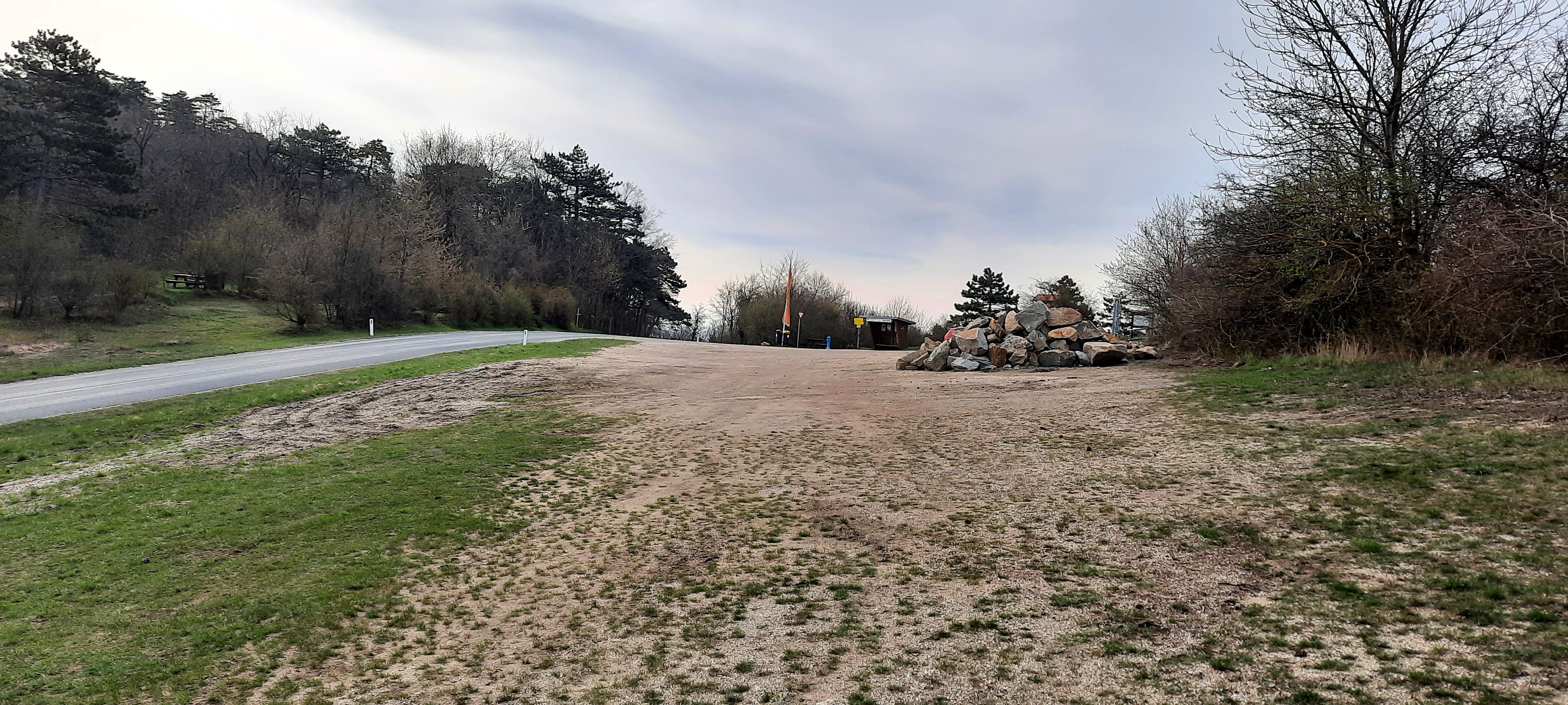 Empty motorhome pitch with trees and road.