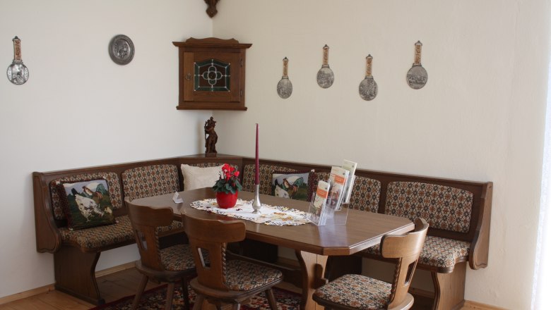 Traditional dining room with wooden furniture, corner bench and decorative wall plates.