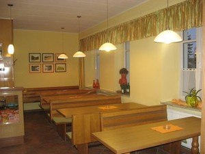 Interior view of a cozy caf&eacute; with wooden tables and benches, decorated with pictures and plants.