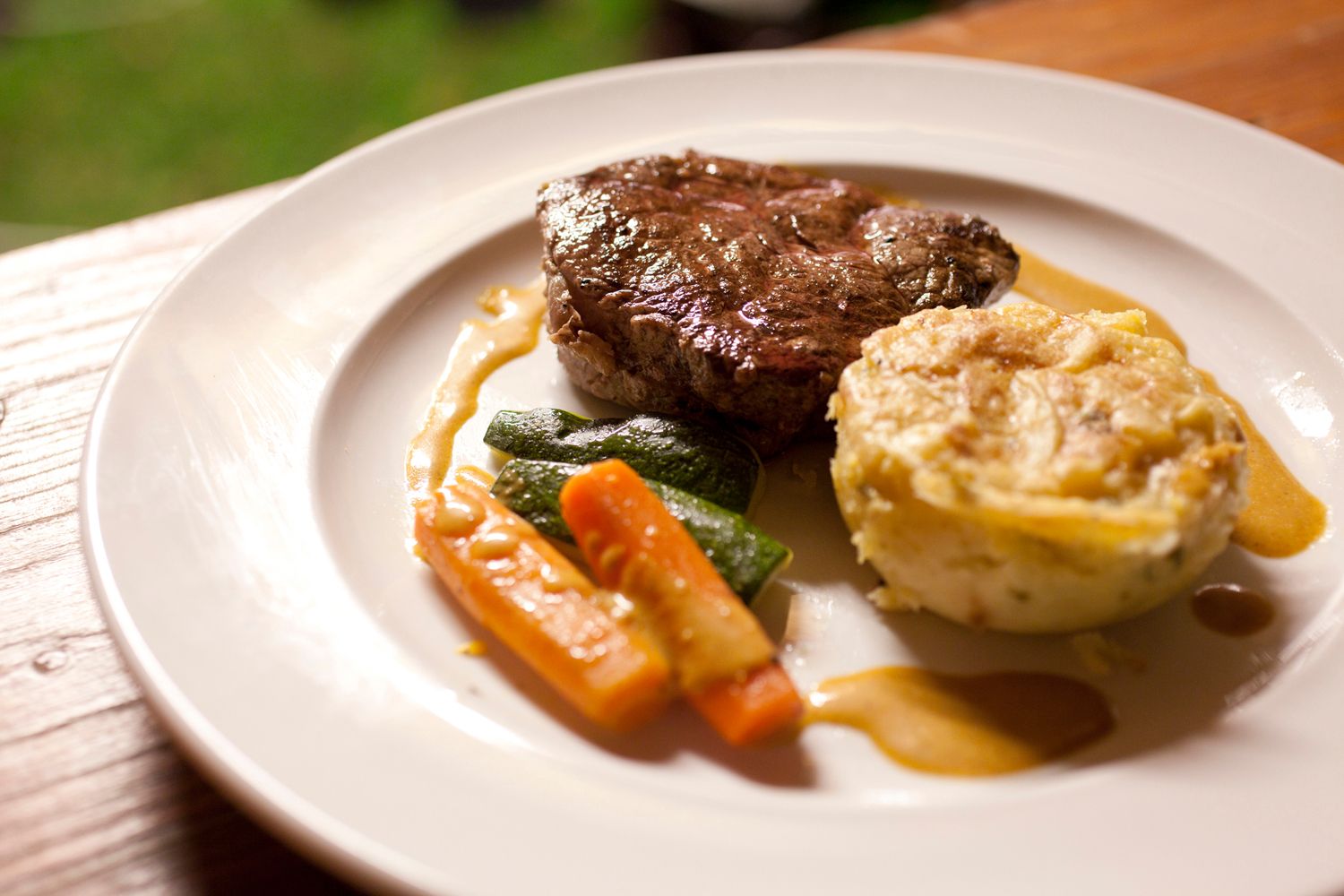 A plate of steak, vegetables and potato gratin.