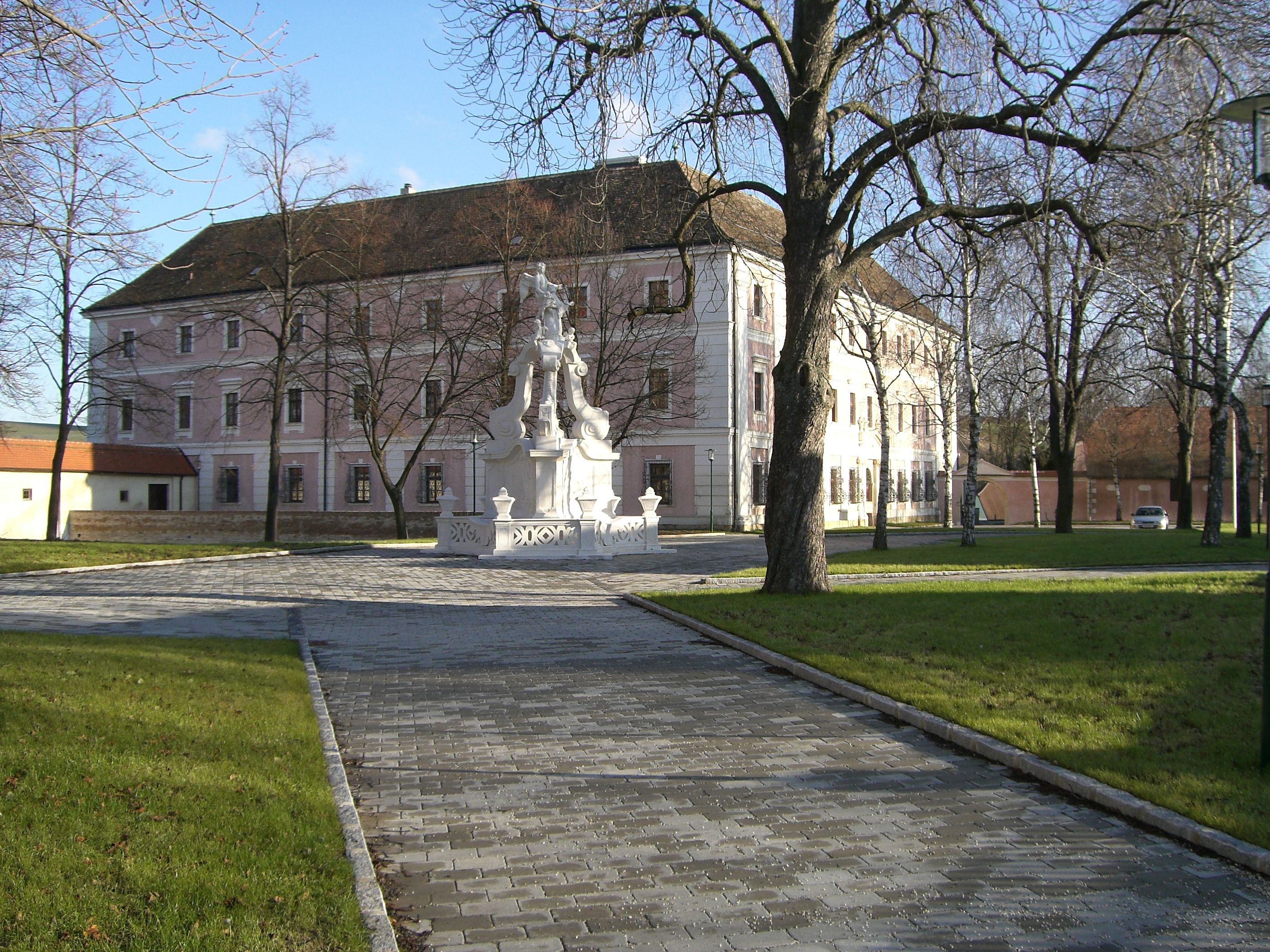 Ein historisches Gebäude mit rosa Fassade und einem Brunnen im Vordergrund.
