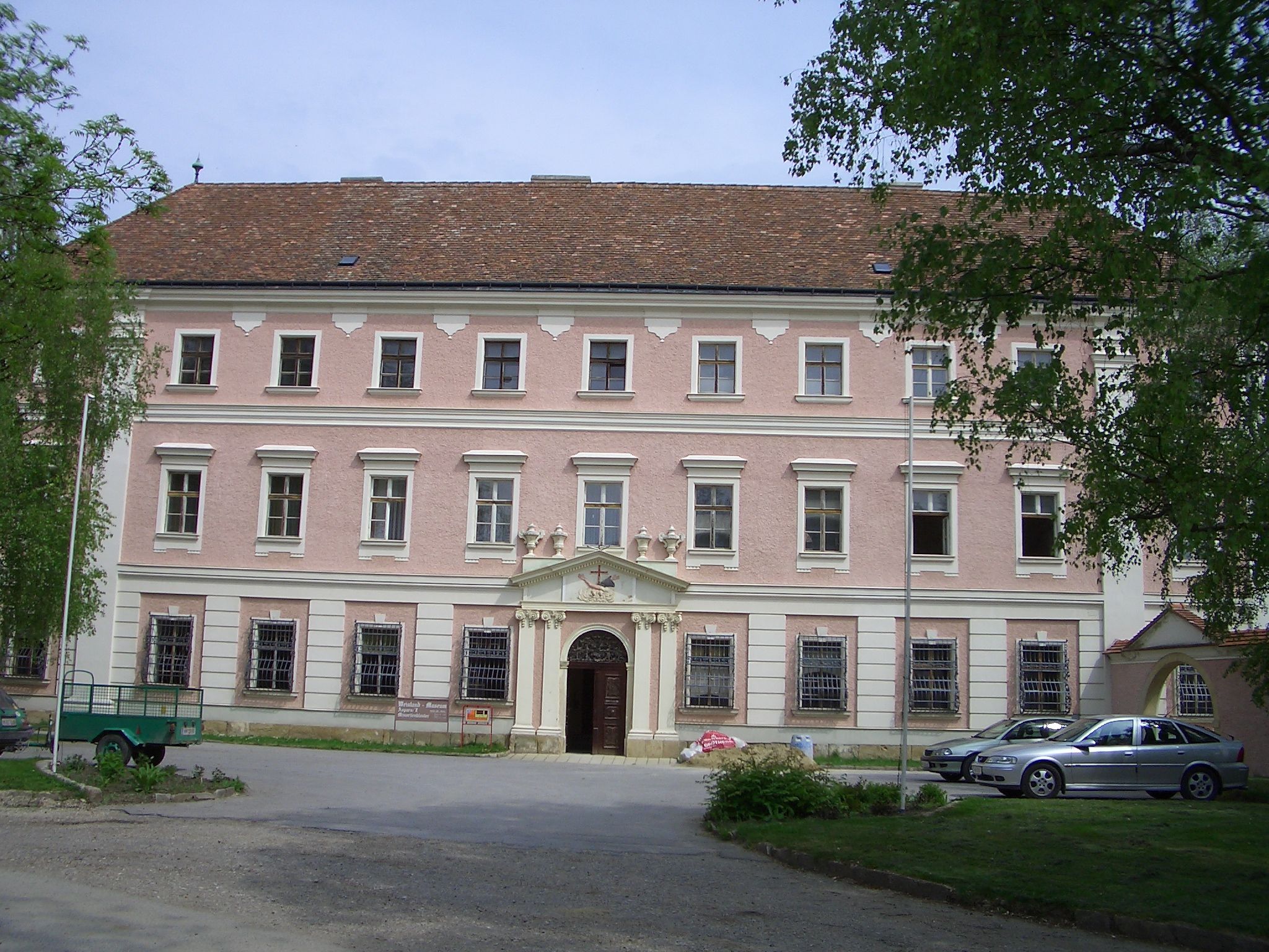 Fassade eines historischen Gebäudes mit rosa Putz und weißen Fensterrahmen.