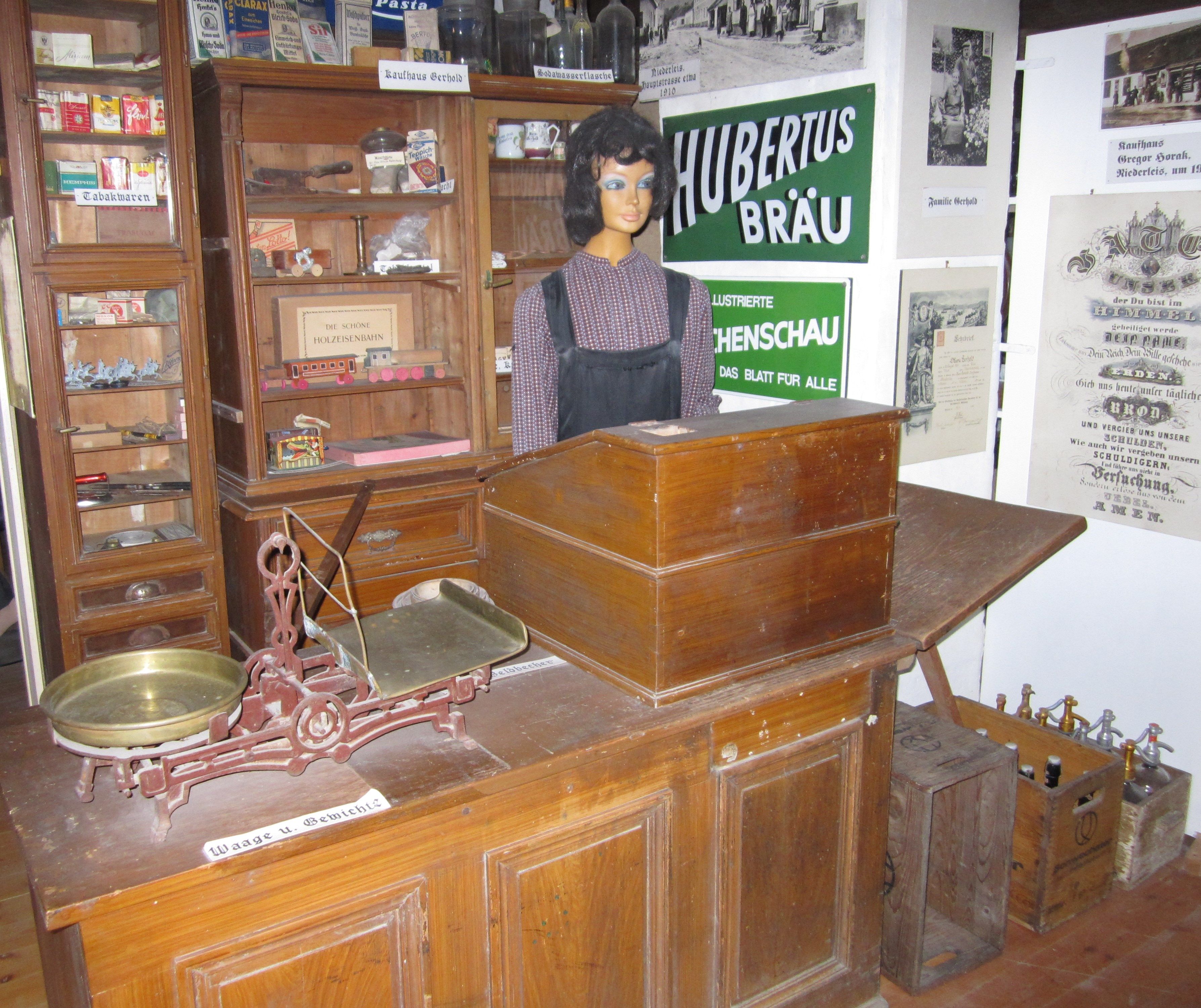 Historischer Laden im Heimatmuseum Niederleis mit Waage, Schaufensterpuppe und alten Werbeschildern.