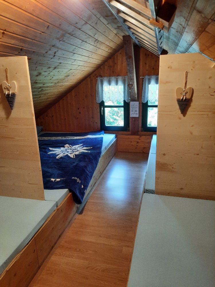 Ein gemütliches Matratzenlager in einem Dachgeschoss mit Holzverkleidung und zwei Fenstern.