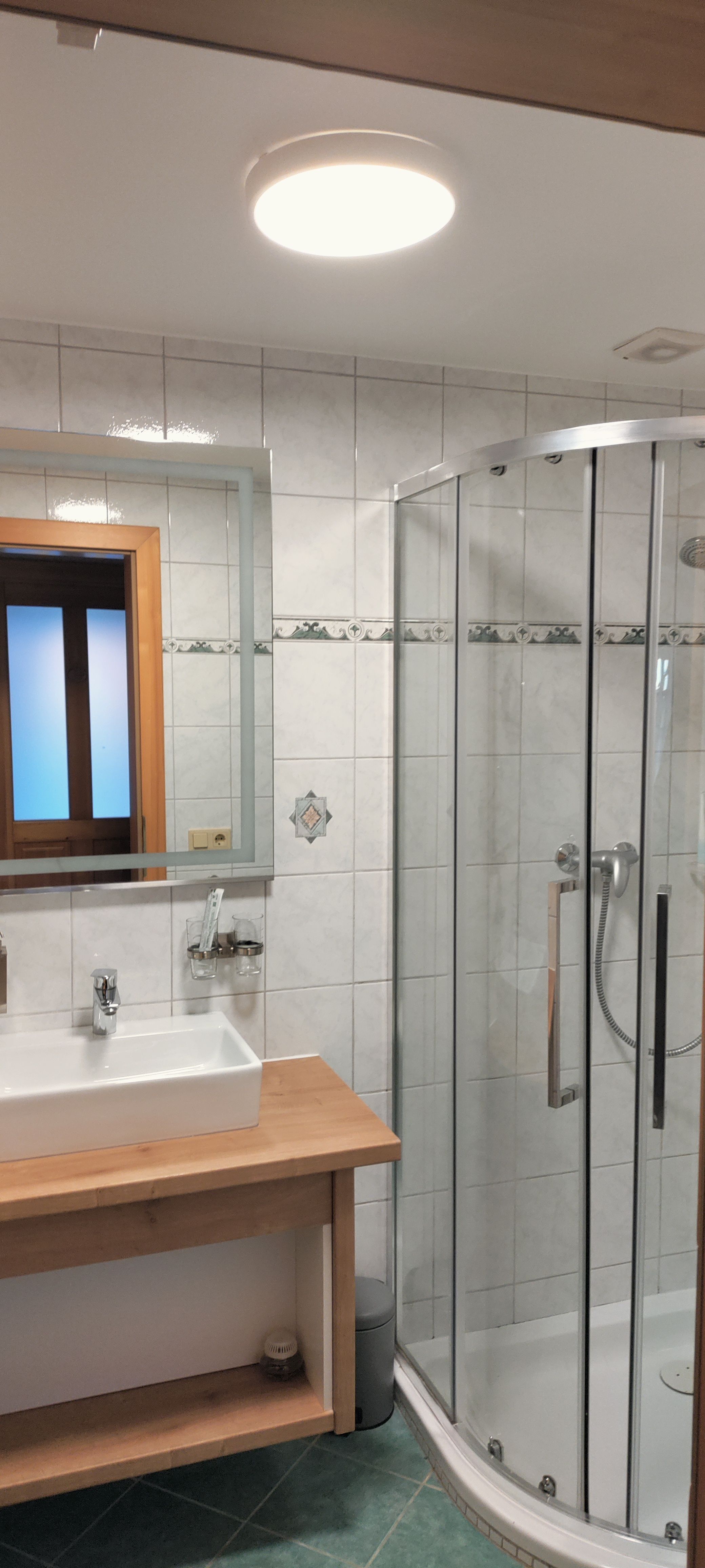 Modernes Badezimmer mit Dusche, Waschbecken und Spiegel.