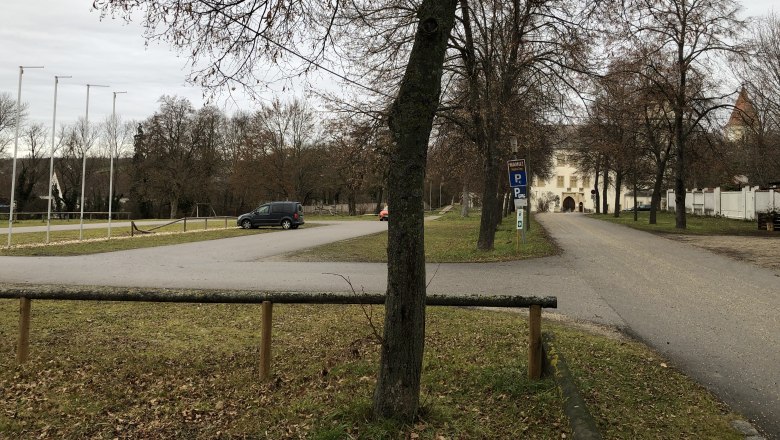 Parkplatz mit B&auml;umen und einem Geb&auml;ude im Hintergrund.