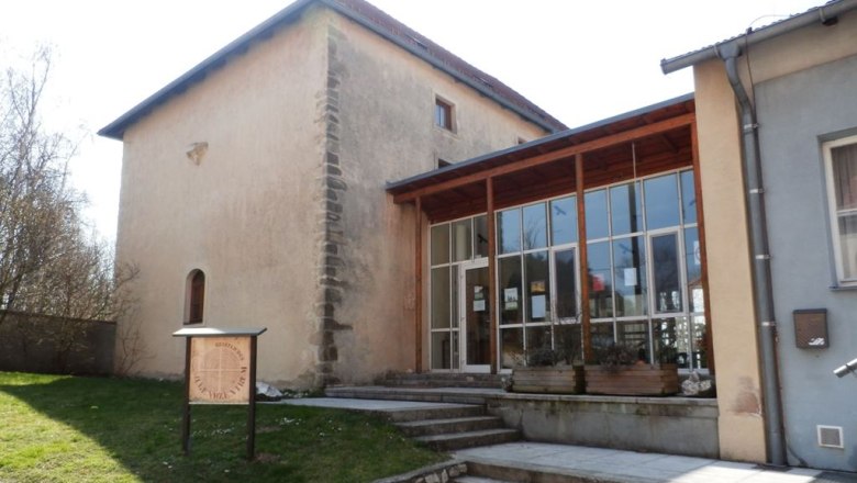 A historic building with a modern extension and a sign in the foreground.