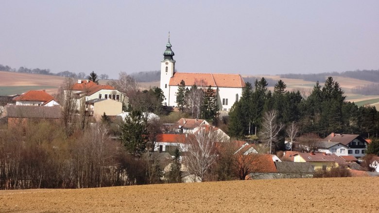 Blick auf das Dorf Gnadendorf mit Kirche und umliegenden Häusern in ländlicher Landschaft.