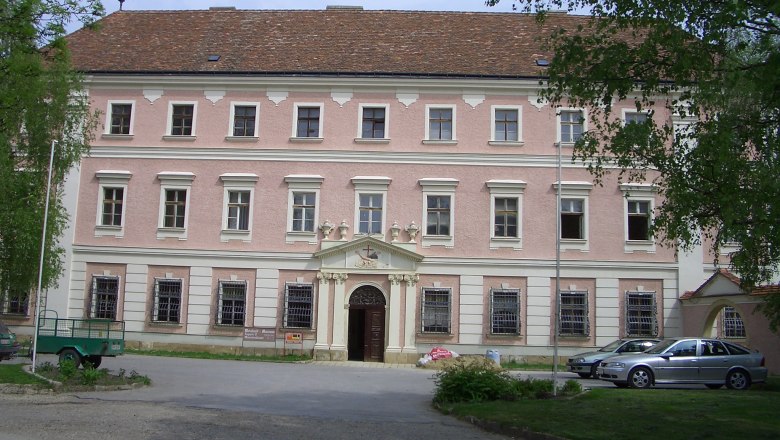 Façade of a historic building with pink plaster and white window frames.