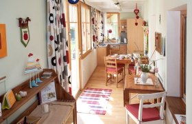 Gem&uuml;tliche Ferienwohnung mit Holzm&ouml;beln, Esstisch und dekorativen Vorh&auml;ngen.