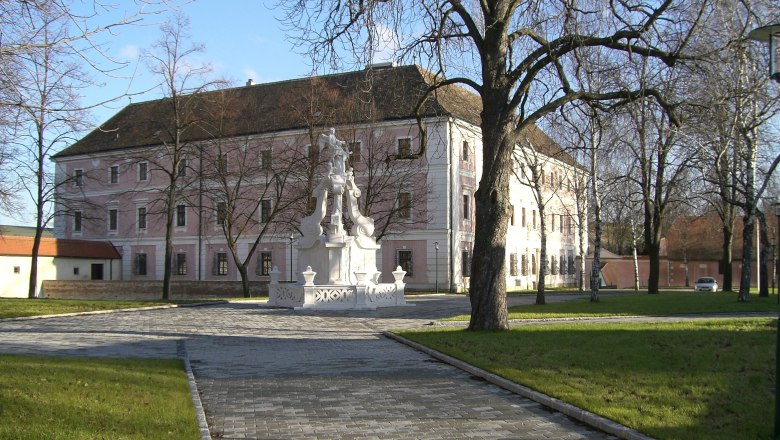 Ein historisches Geb&auml;ude mit rosa Fassade und einem Brunnen im Vordergrund.