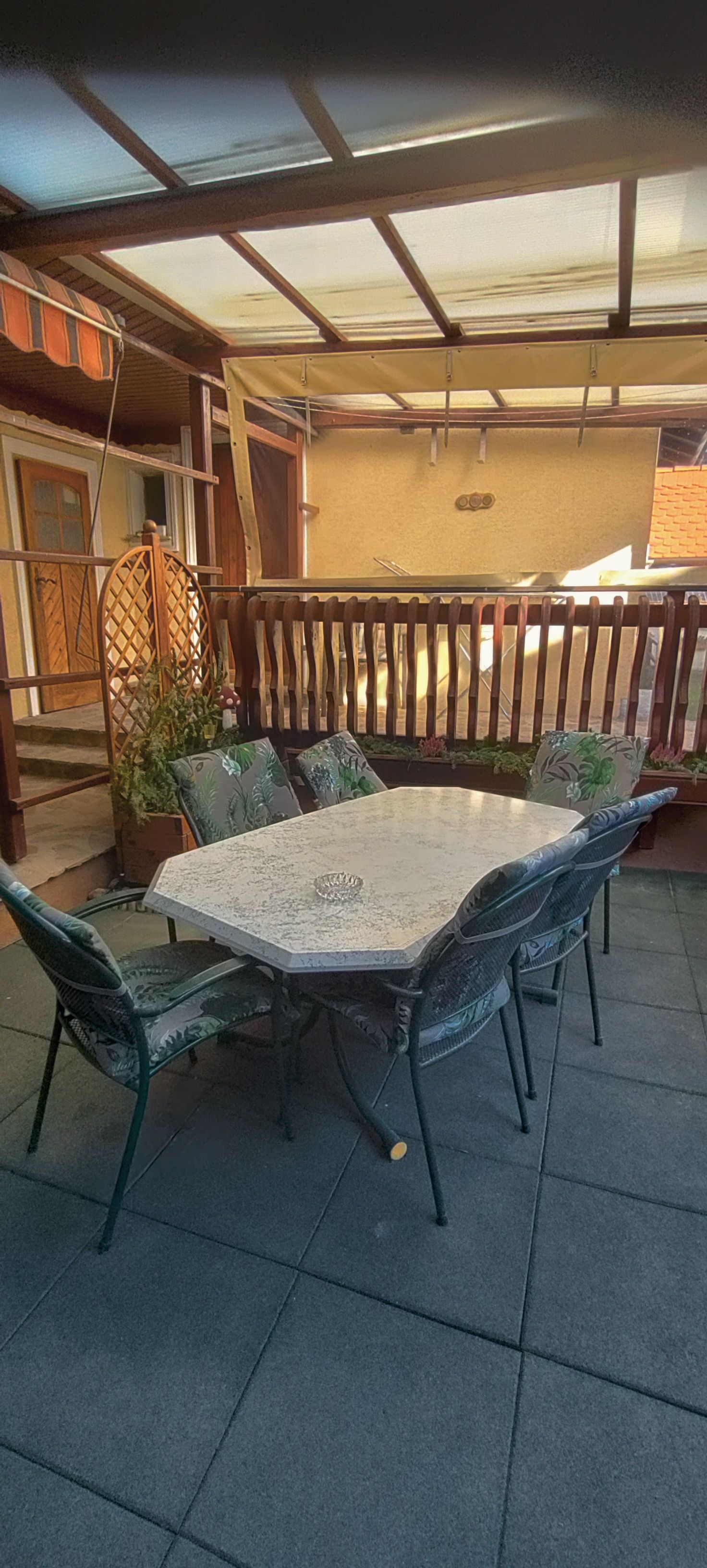 Überdachte Terrasse mit Tisch und Stühlen.