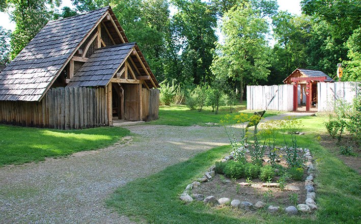 Historic wooden houses in an open-air museum with a garden.