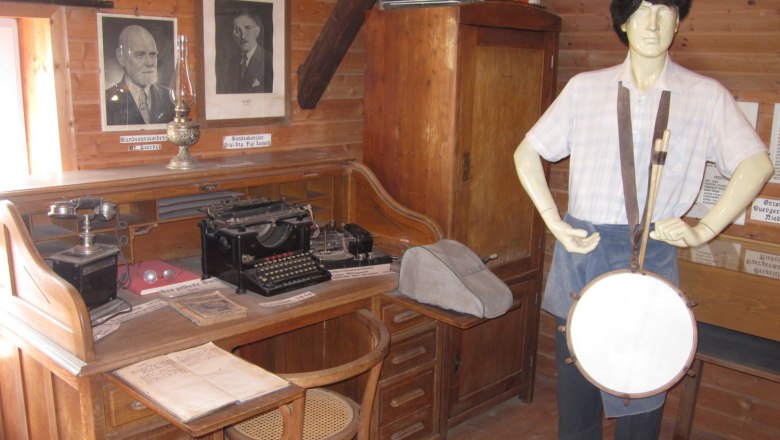Interior view of a museum room with desk, typewriter and mannequin with drum.