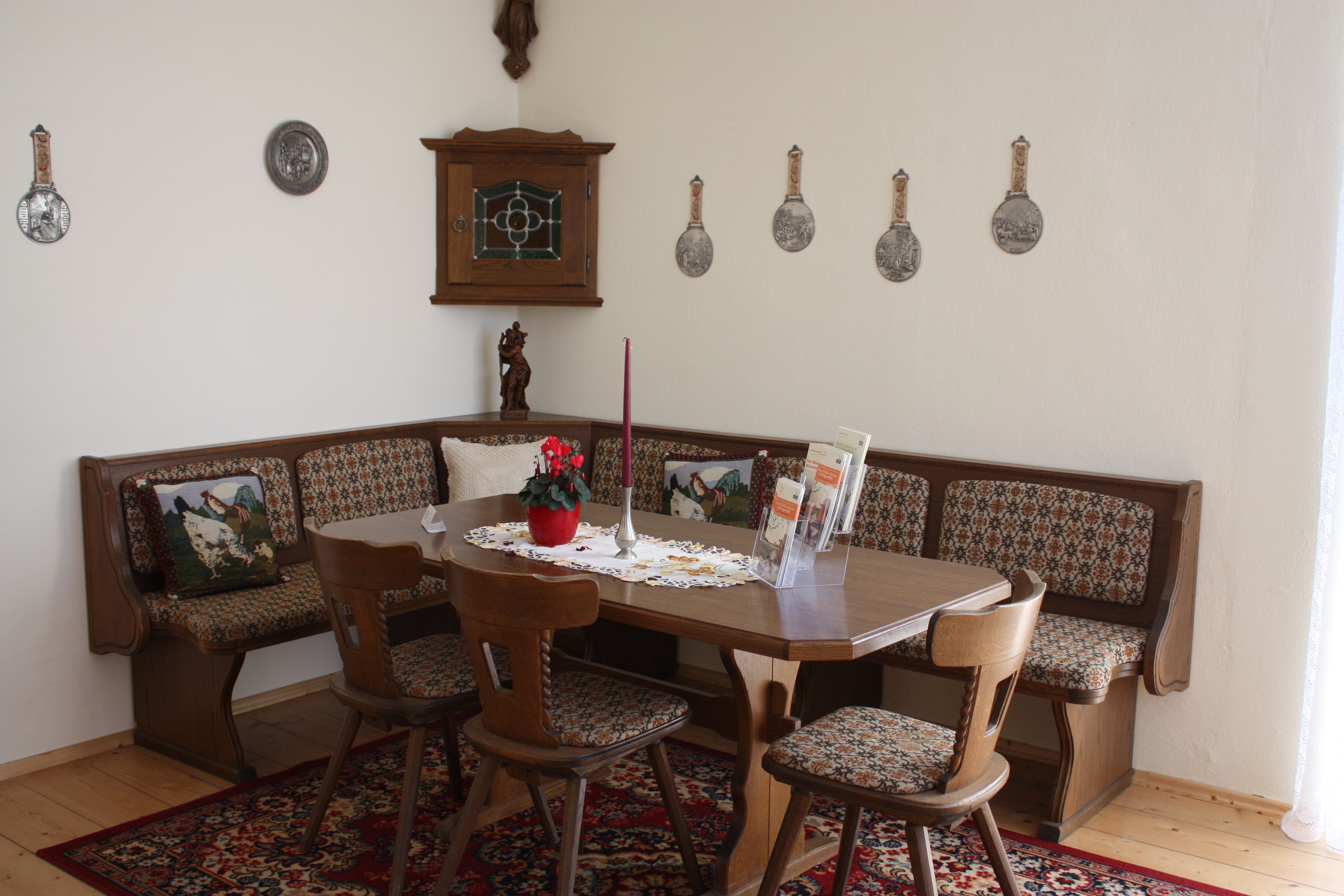Traditionelles Esszimmer mit Holzmöbeln, Eckbank und dekorativen Wandtellern.