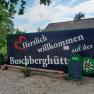 Welcome sign of the Buschbergh&uuml;tte with green surroundings and blue sky.