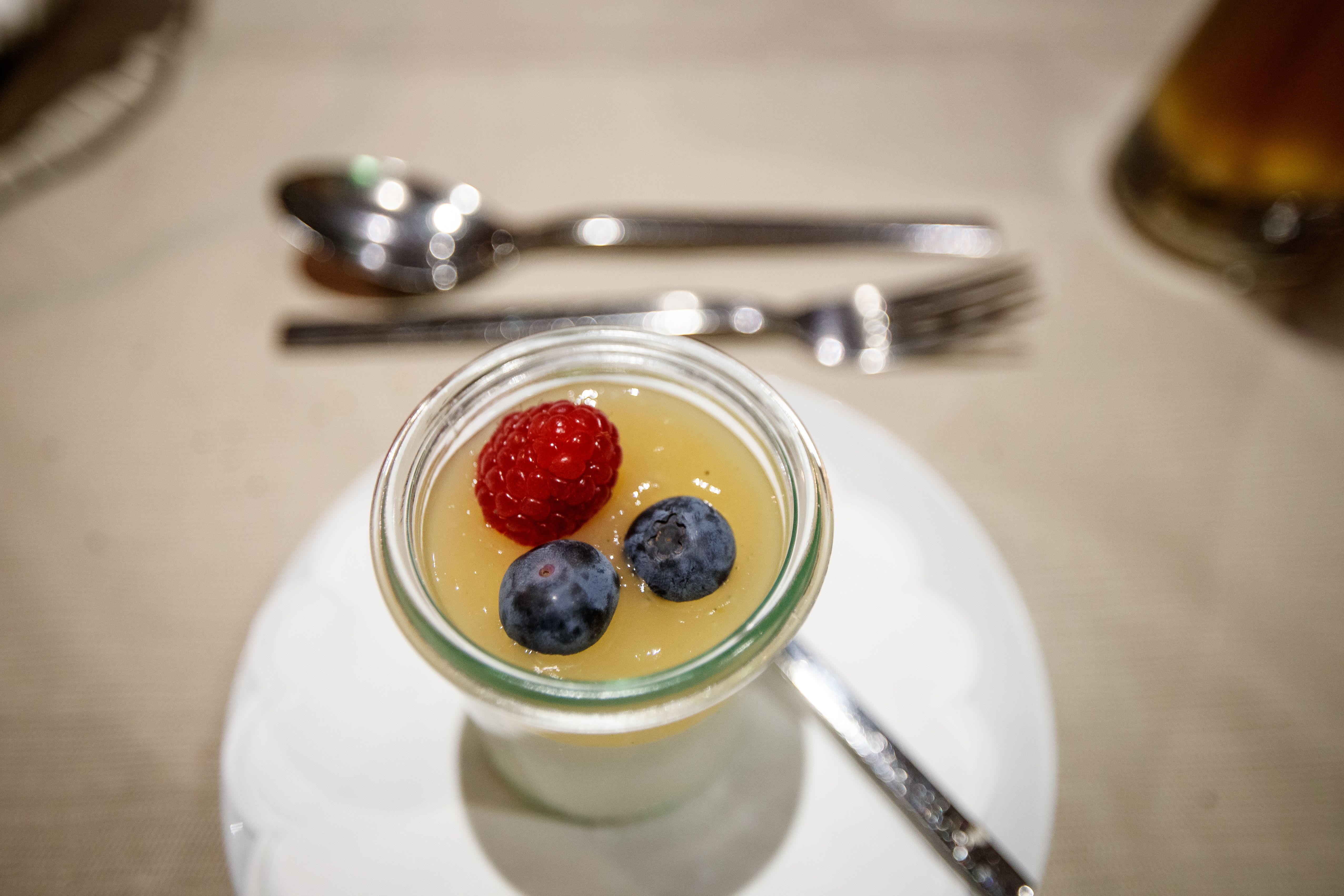 Dessert in a glass with raspberry and blueberries on a tablecloth.