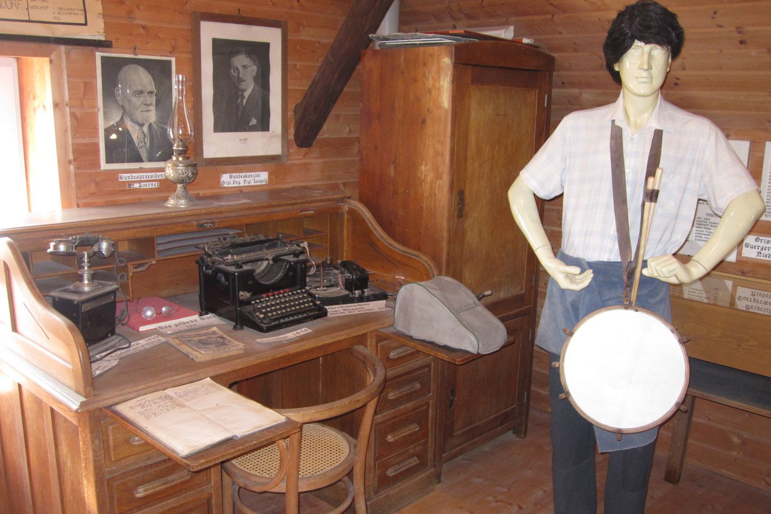 Innenansicht eines Museumsraums mit Schreibtisch, Schreibmaschine und Schaufensterpuppe mit Trommel.