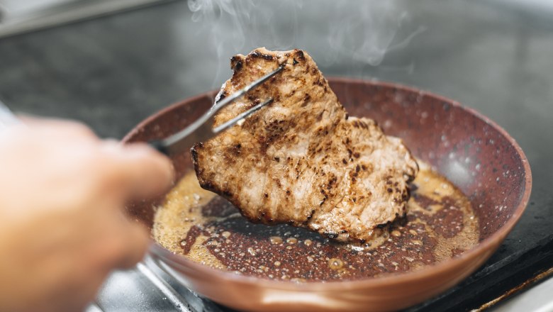 A piece of meat is fried in a pan.