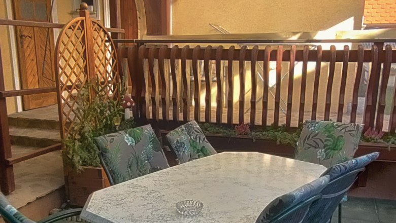 &Uuml;berdachte Terrasse mit Tisch und St&uuml;hlen.