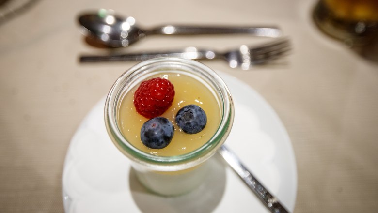 Dessert im Glas mit Himbeere und Blaubeeren auf einer Tischdecke.
