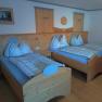 Comfortable bedroom with two single beds made of wood, bedside table and chest of drawers.