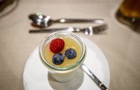 Dessert im Glas mit Himbeere und Blaubeeren auf einer Tischdecke.