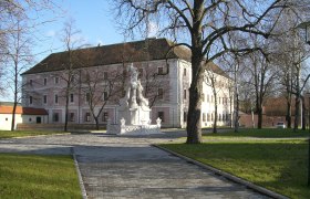 Ein historisches Geb&auml;ude mit rosa Fassade und einem Brunnen im Vordergrund.