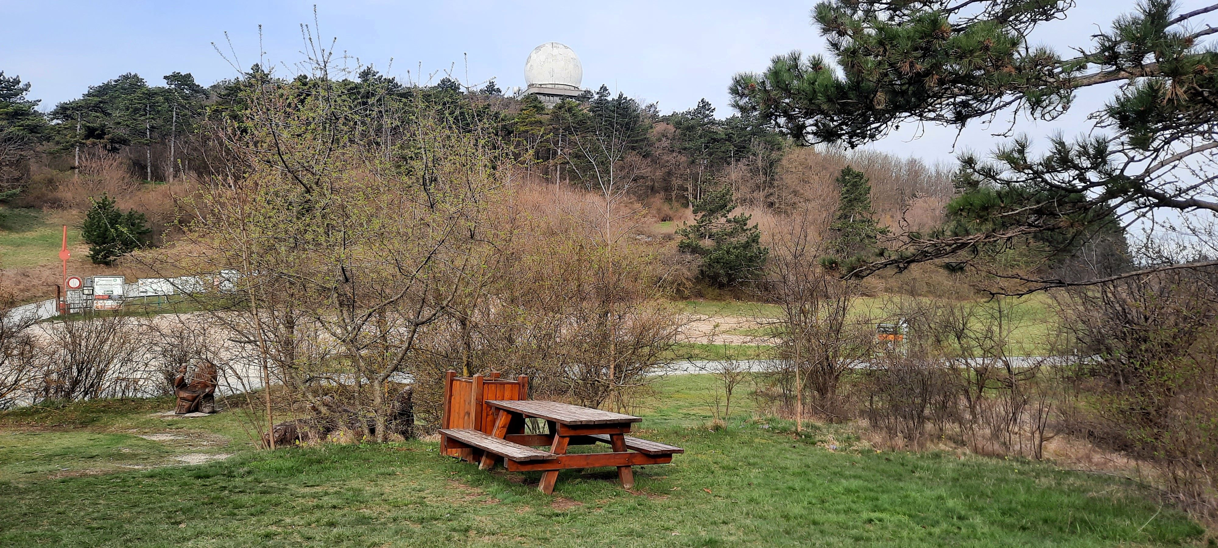 Picnic table on a meadow with trees and a large white radome in the background.