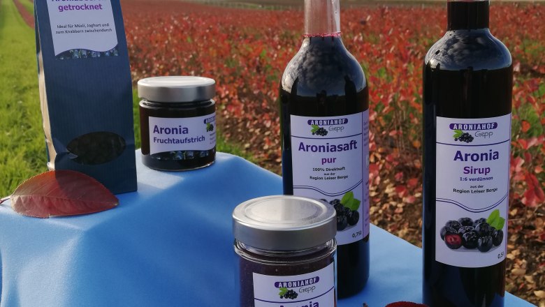 Produkte des Aroniahofs Gepp auf einem Tisch vor einem Feld.