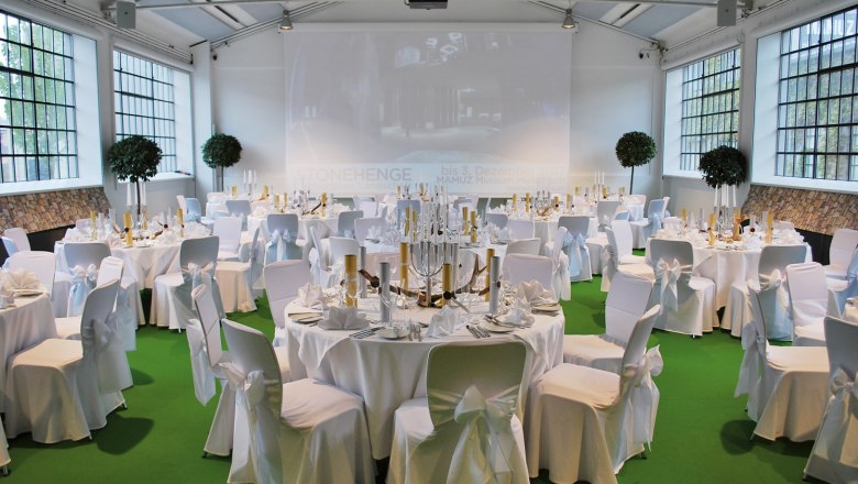 Elegant function room with white tables and a green floor.
