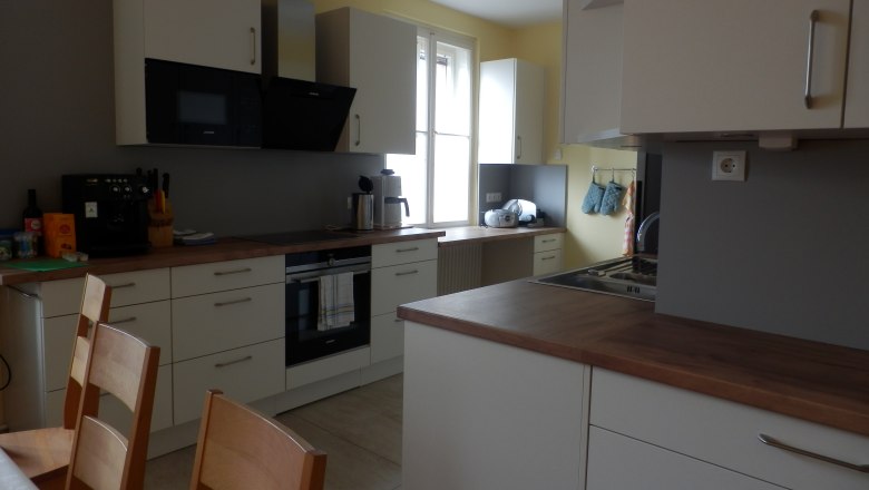 Modern kitchen with white cupboards, wooden worktops and appliances such as coffee machine and oven.